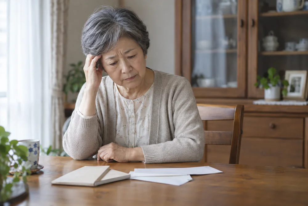 書類を前に不安そうに考え込む女性のイメージ